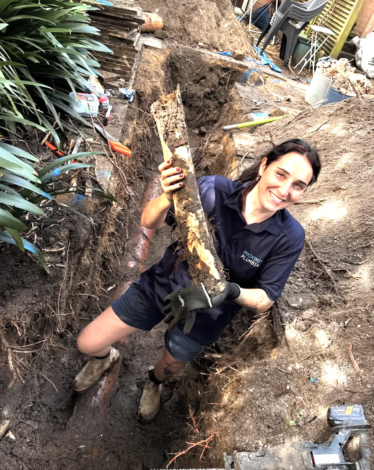 Root-damaged pipework exposed in a garden trench